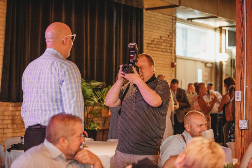 A photographer snaps a photo of a man smiling at a wedding reception in Roanoke, Virginia.