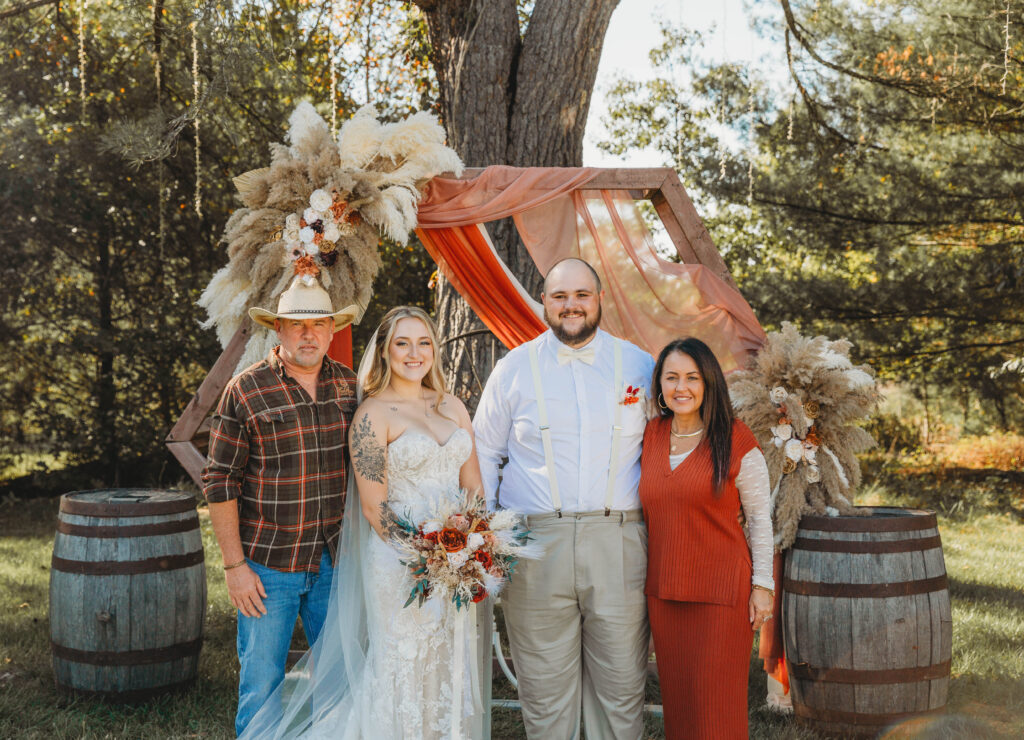 Owners of the venue The Barn on Unity Farm stand beside the bride and groom outside at their venue in Princeton, West Virginia. 