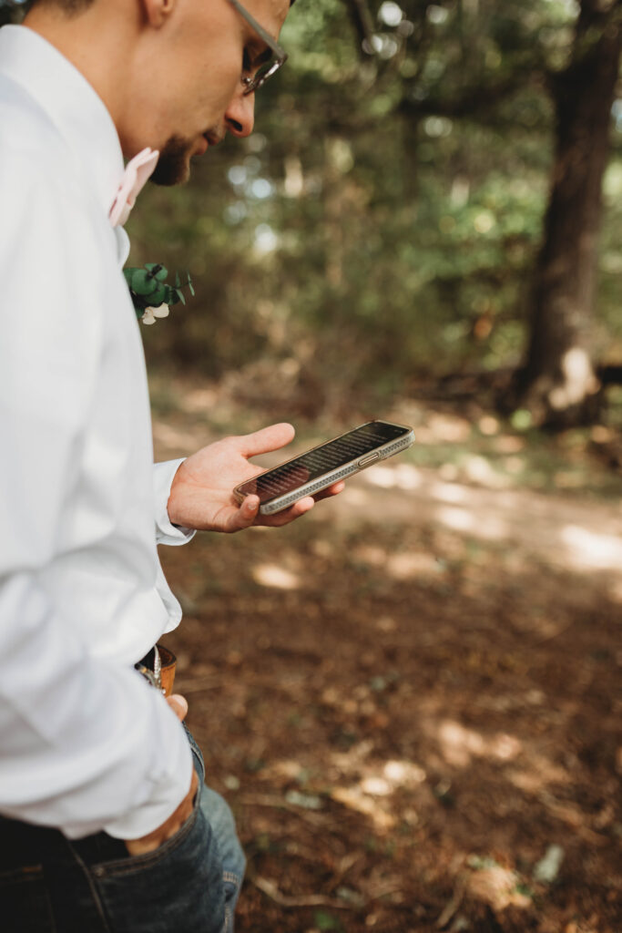 A groom reads his private vows from his phone in the woods in Roanoke, Virginia. 