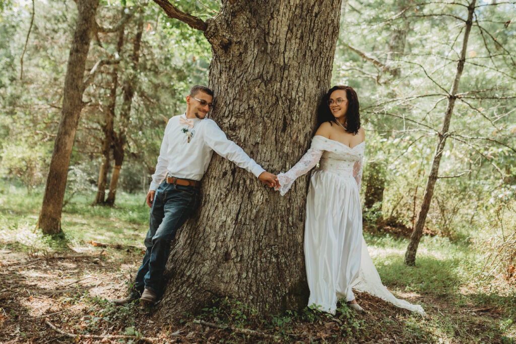 A bride and groom touch on either side of a tree before seeing each other for the first time before the wedding. 