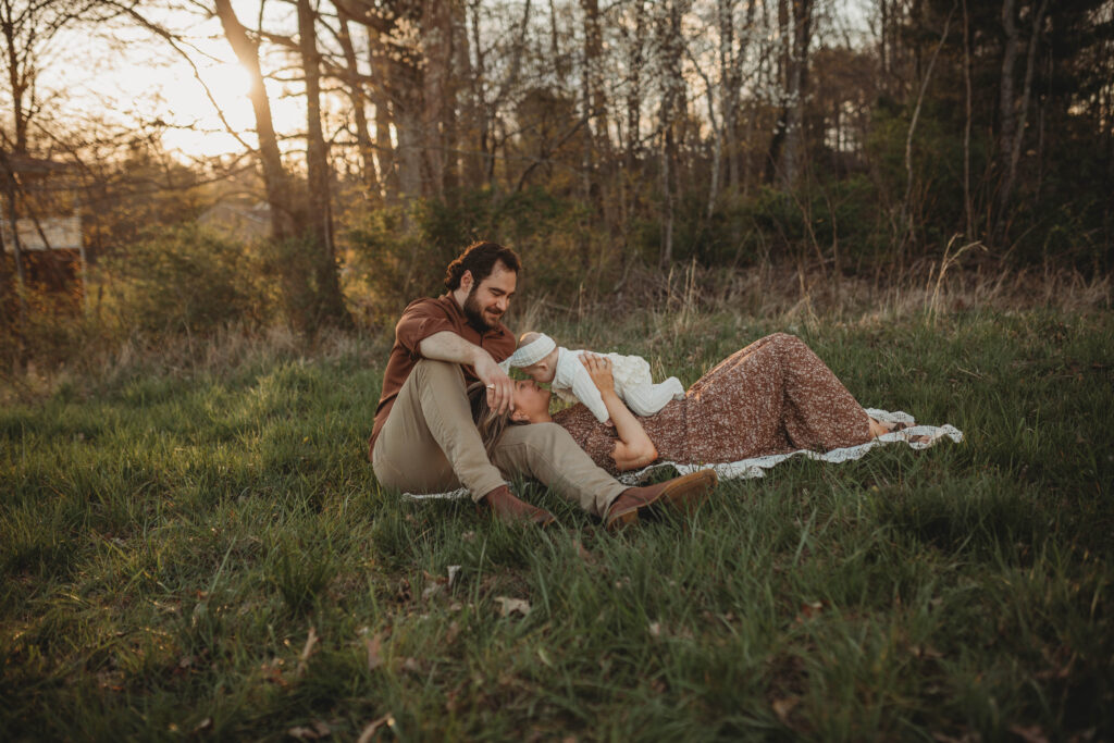 A family play with their baby while lounging on a blanket in a field of grass in Beckley, West Virginia. 