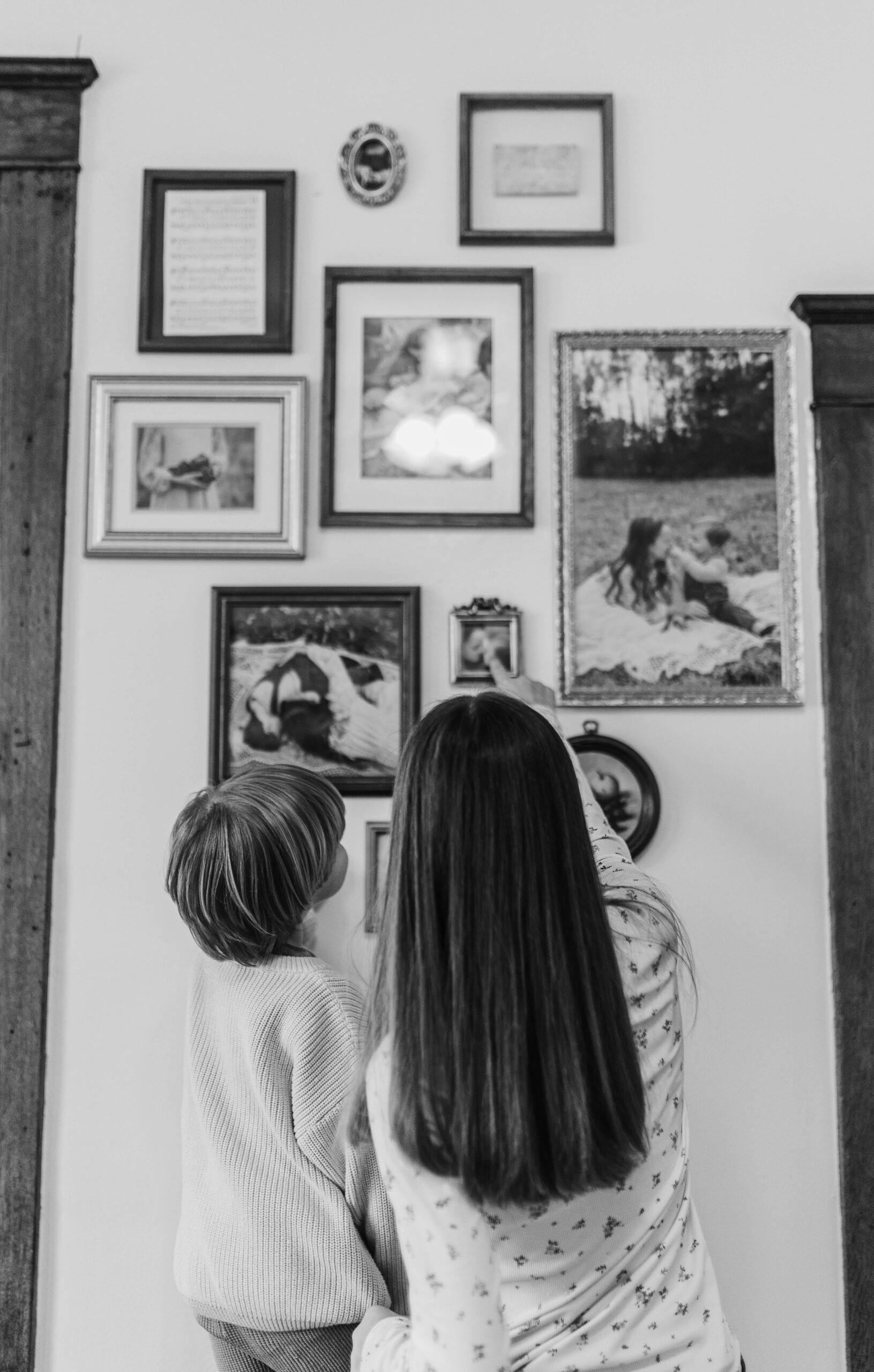A boy and girl pointing at images on them on the wall of their home.