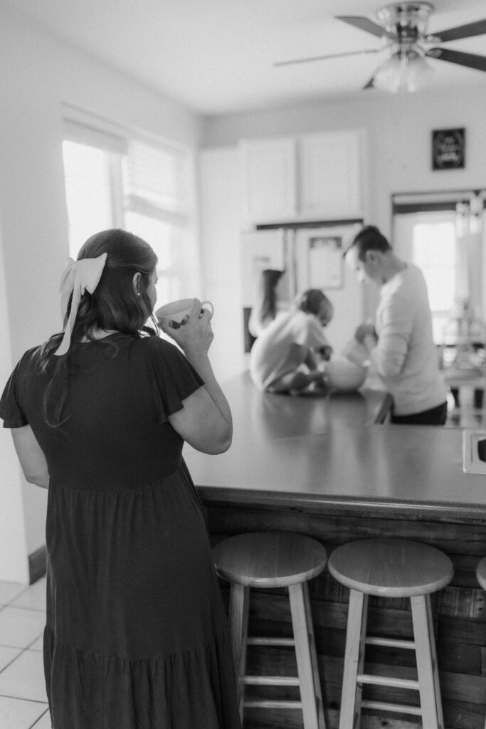 A mother sipping coffee and watching her family at an in home family photography session in Bluefield, West Virginia.