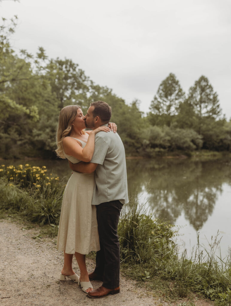 A couple embrace and kiss beside a pond at Heritage Community Park in Blacksburg, Virginia.