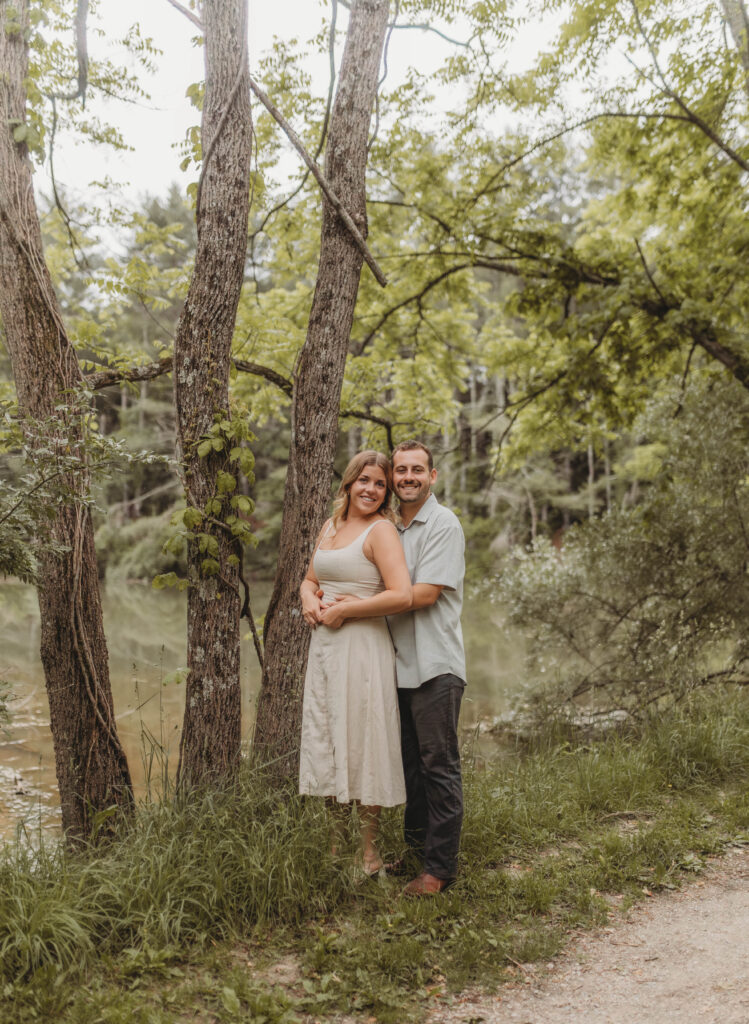 A woman and man look at the camera and smile during engagement photos at Heritage Community Park in Blacksburg, Virginia.
