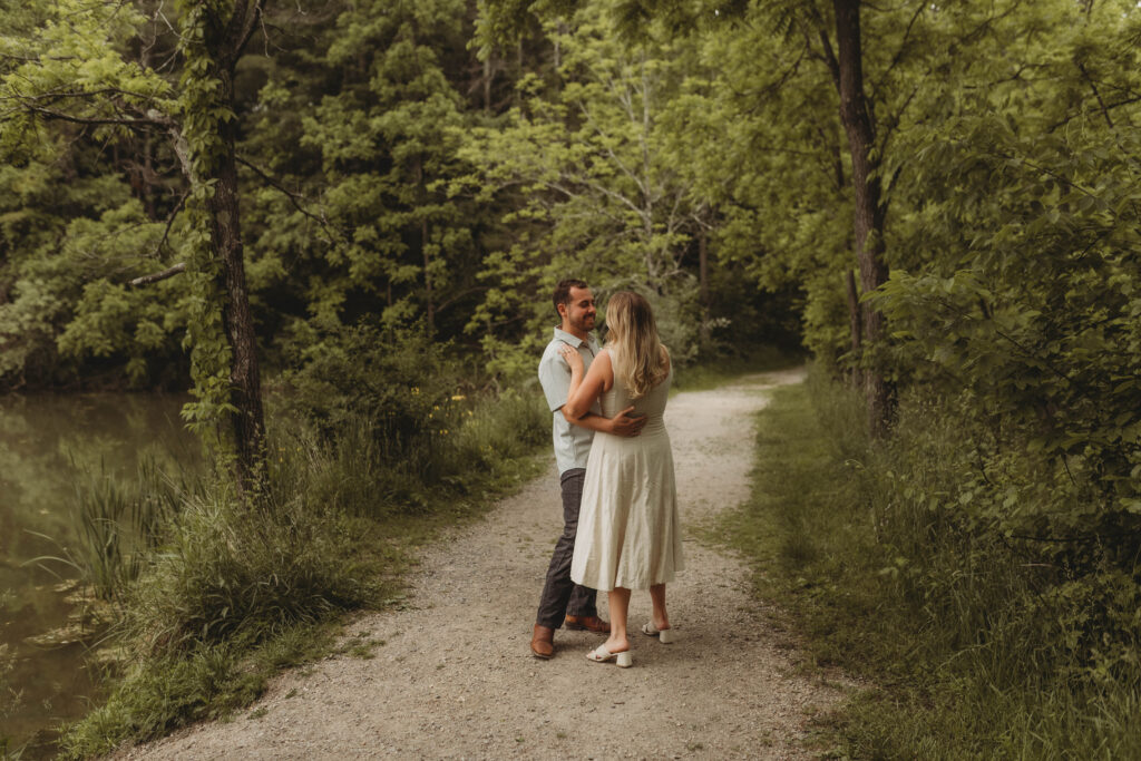 A couple dance and play together on a trail with lake in the background at Heritage Community Park in Blacksburg, Virginia.