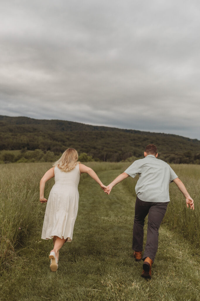 A couple hold hands and run away into a field at Heritage Community Park in Blacksburg, Virginia.