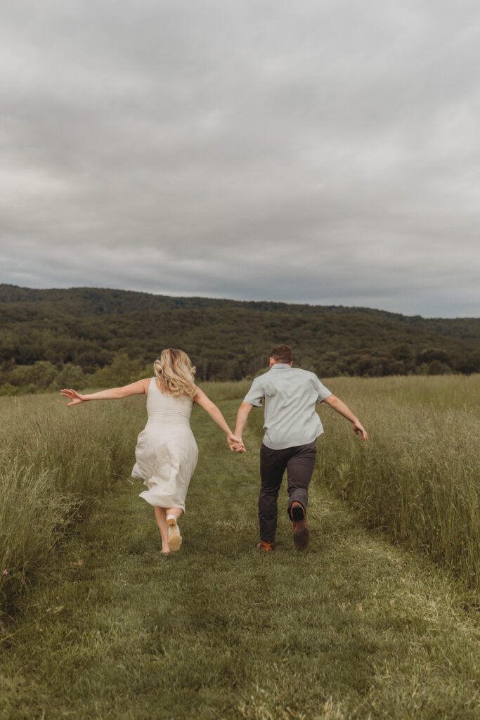 A couple hold hands and run away into a field at Heritage Community Park in Blacksburg, Virginia.