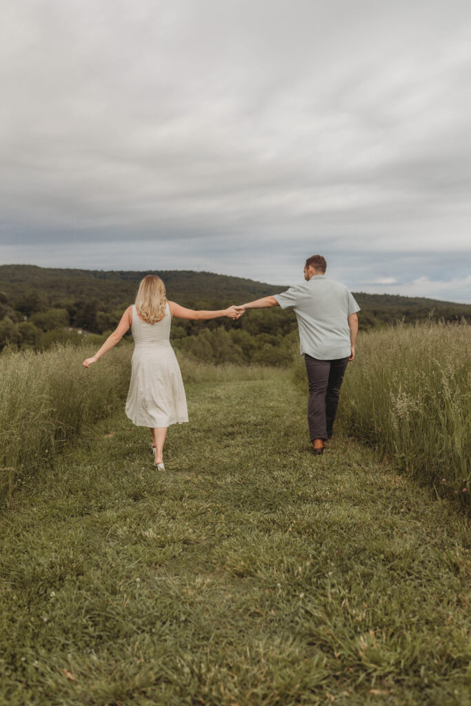 A couple hold hands and walk away into a field at Heritage Community Park in Blacksburg, Virginia.
