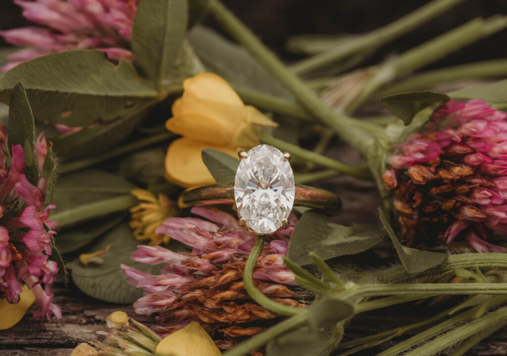A beautiful golden diamond ring sitting on wildflowers during engagement photos in Blacksburg, Virginia.