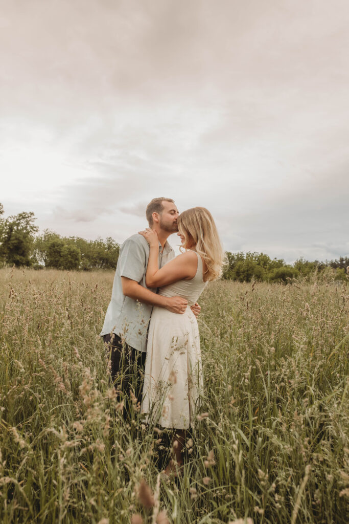 A man kisses a woman's forehead during engagement photos at Heritage Community Park in Blacksburg, Virginia.