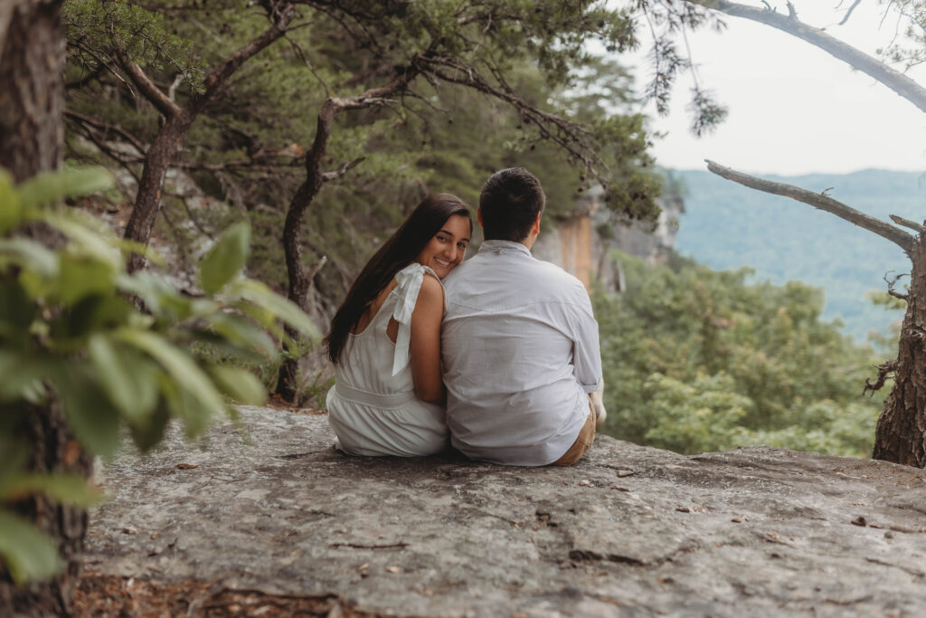 A woman leans on her finance and looks at the camera at the New River Gorge.