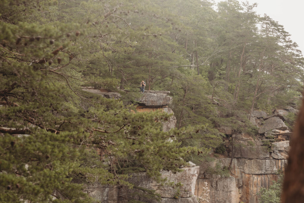 New River Gorge Engagement Photograph bends down on one knee to photograph moment.