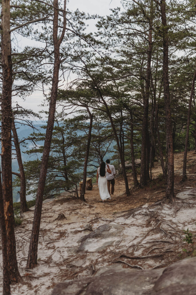 A couple walks toward the New River together during their New River Gorge engagement photos.