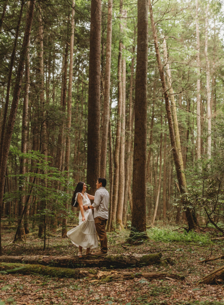 A couple dances on a log during New River Gorge engagement photos.