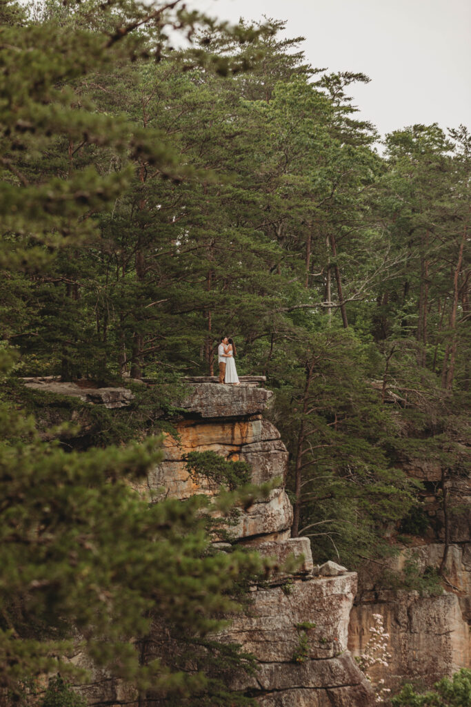 Couple from a far away angle on a cliff at the New River Gorge.