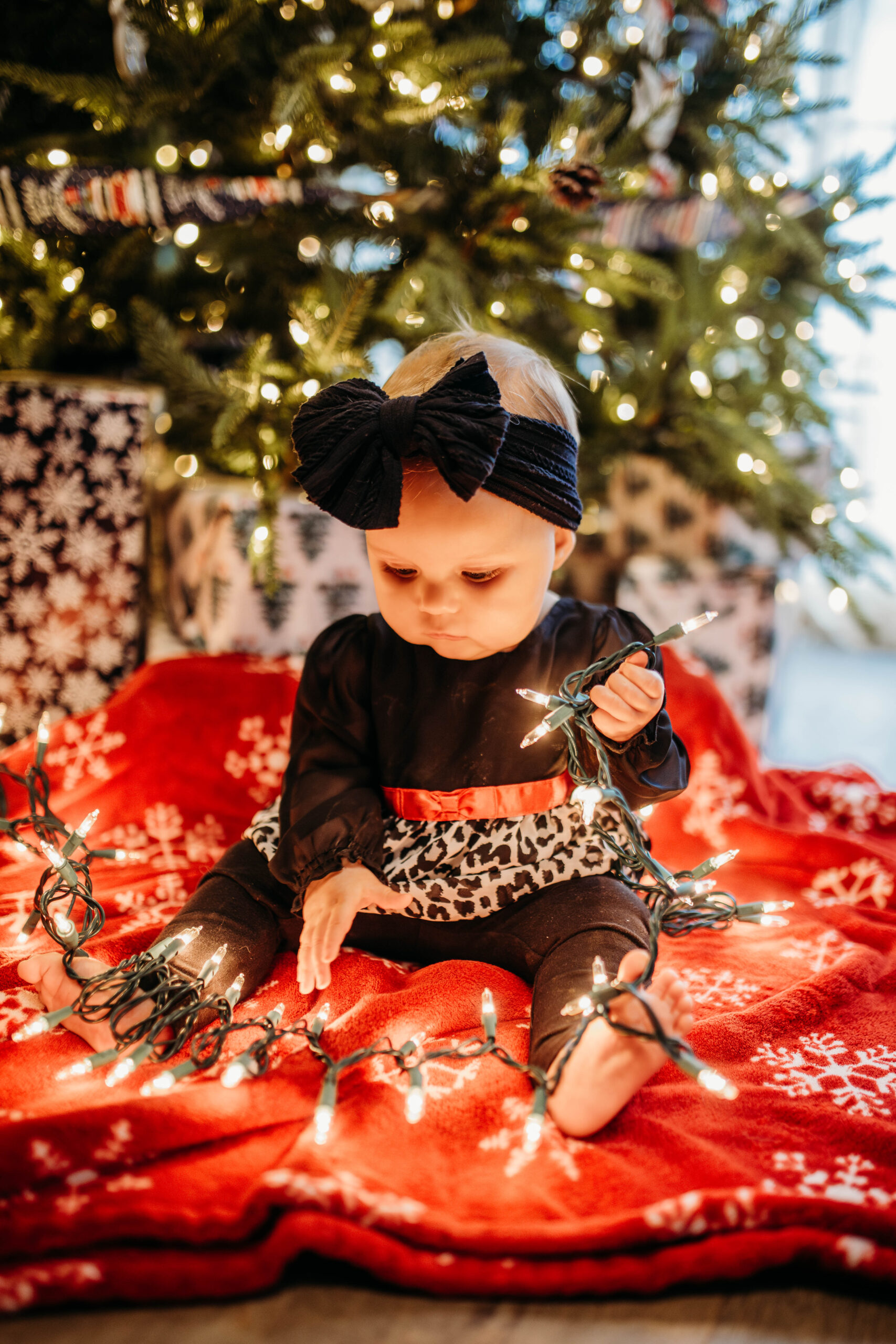 A baby plays with lights at an at home winter photo session.