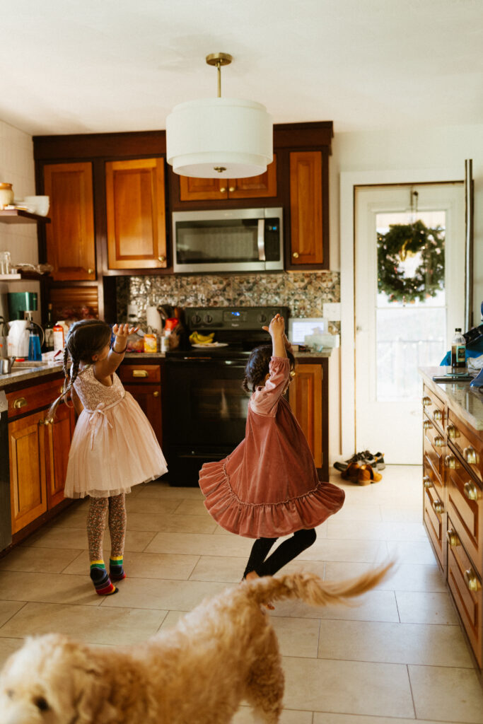Two children are dancing in their kitchen freely during in home documentary photos.