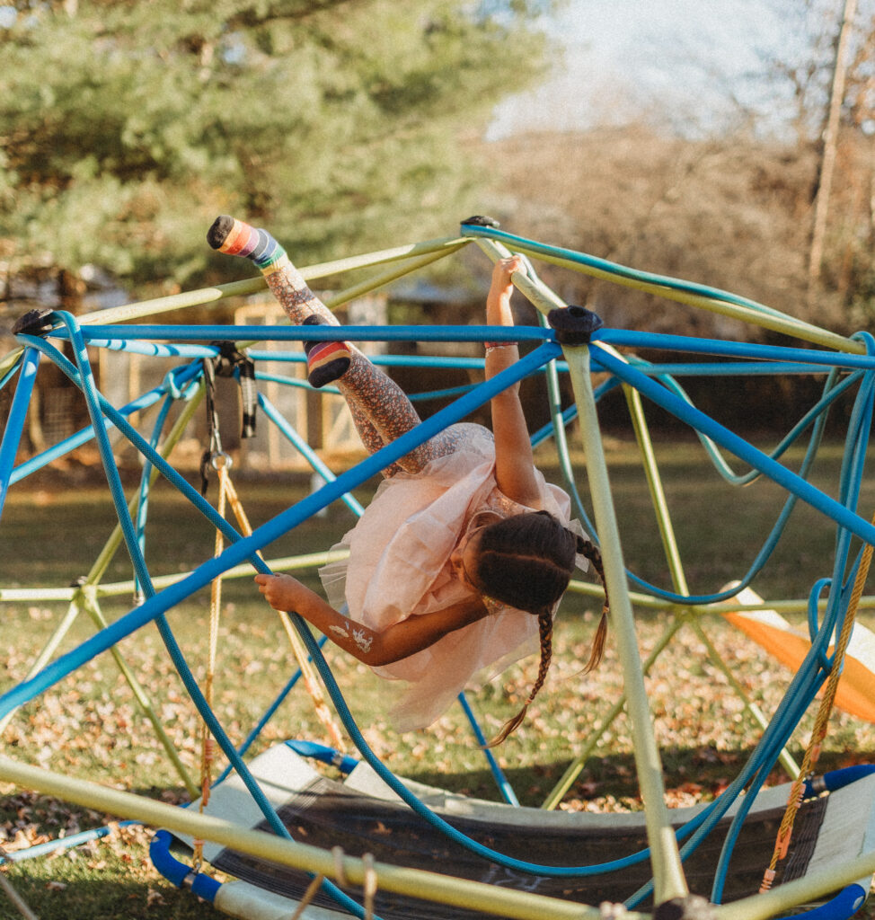 A child is playing on a jungle gym outside of the family's home during in home documentary photos.