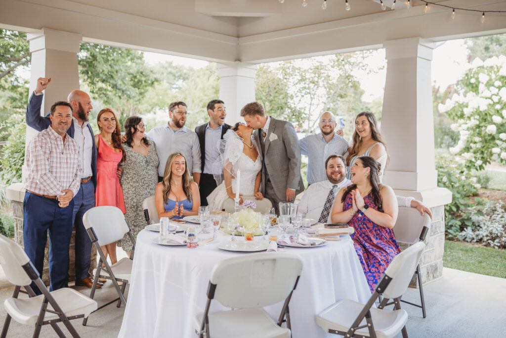 Friends cheer a bride and groom on for a kiss at a Hahn Horticulture Wedding in Blacksburg, Virginia. 