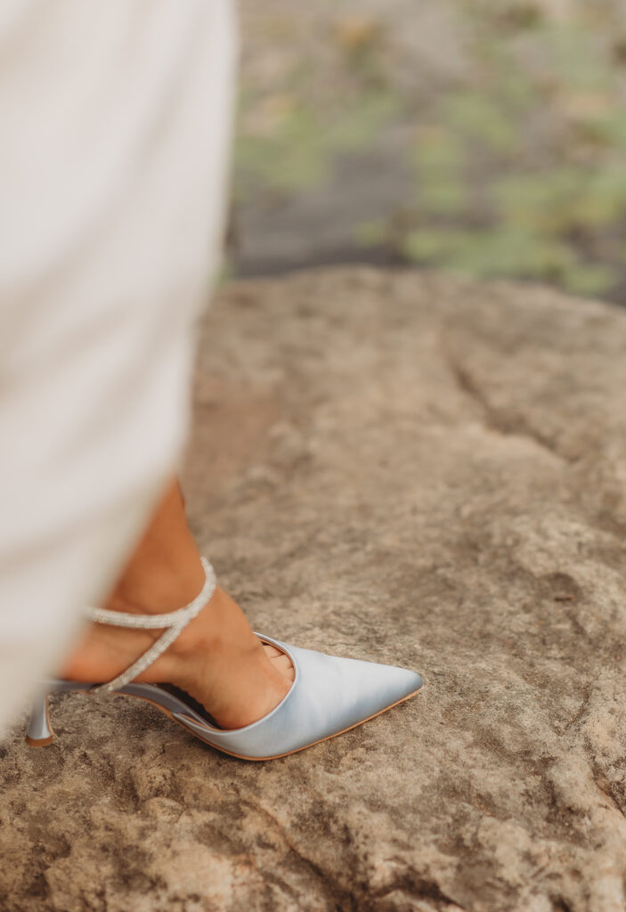 The bride slips her shoe on near the creek at a Hahn Horticulture Wedding in Blacksburg, Virginia. 