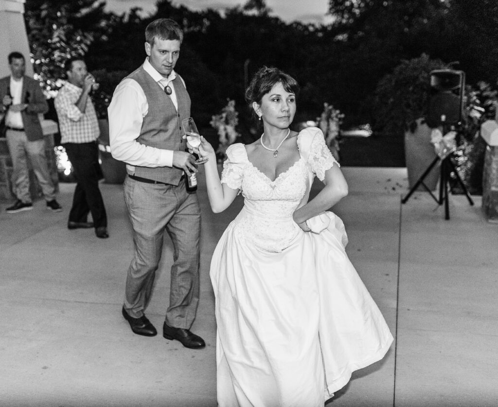 Bride holds champagne and dances at a Hahn Horticulture Wedding in Blacksburg, Virginia. 