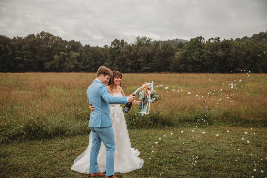The bride and groom op champagne in a field