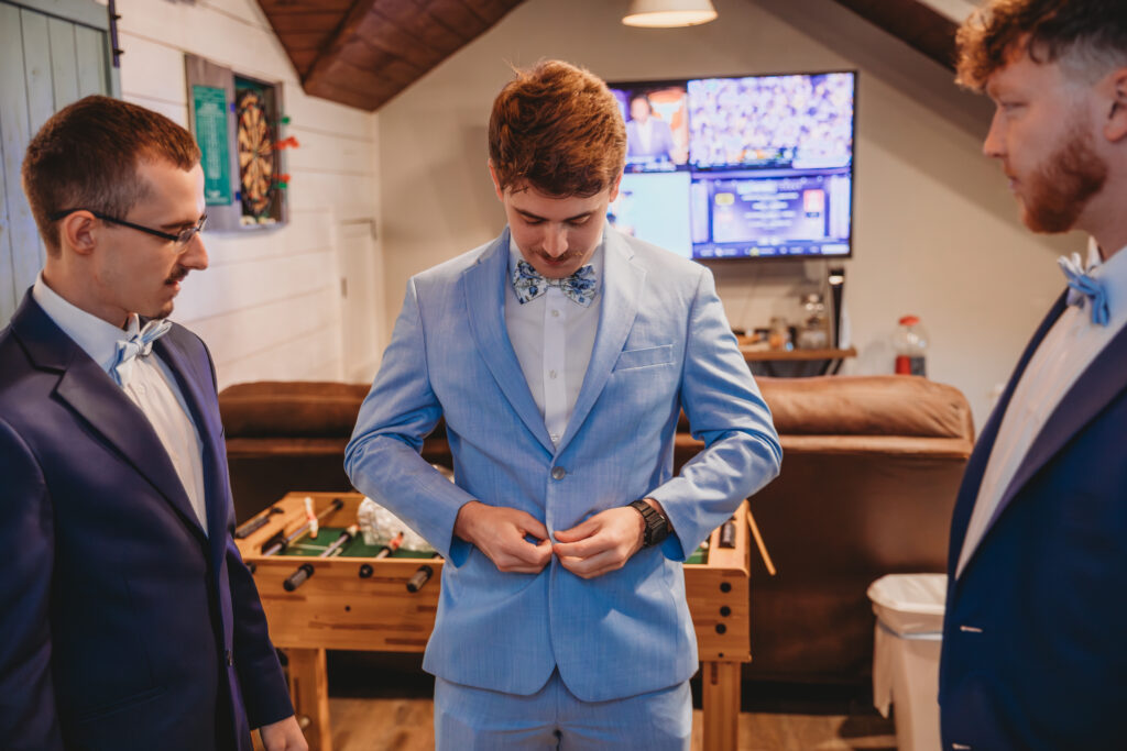 Groom buttoning his shirt at a Vintage Valley Wedding. 