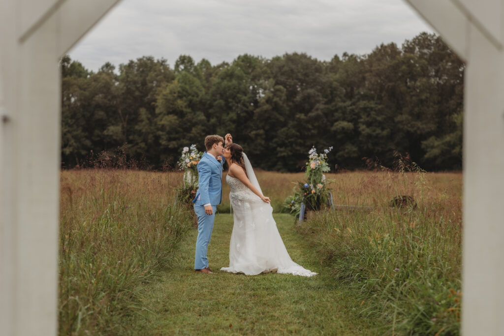 The bride and groom kiss in a field