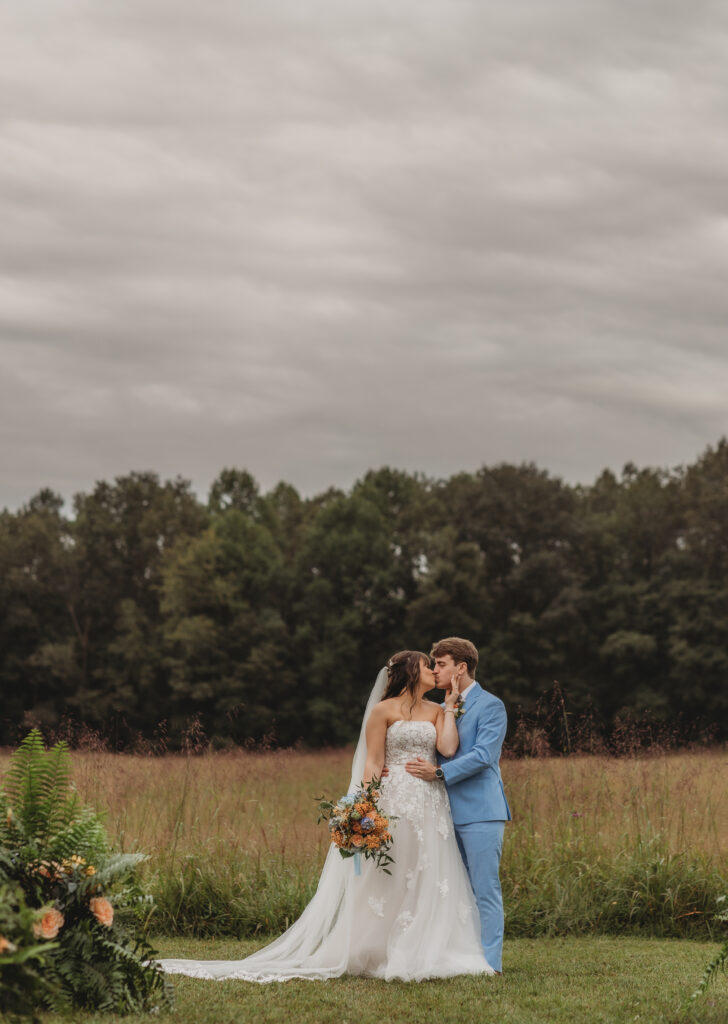 The bride and groom kiss in a field