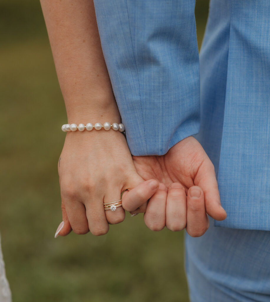 The bride and groom hold pinkies