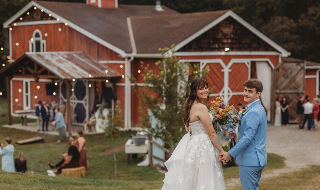 A couple holding hands with the West Virgina Wedding Venue, Vintage Valley Weddings, in the background.